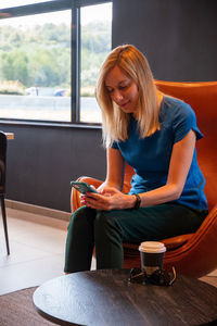 Positive blonde businesswoman holding a mobile phone,happy to receive a message