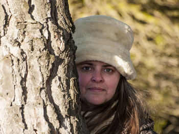 Portrait of mature woman behind tree trunk