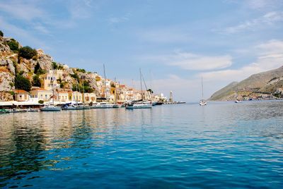 Sailboats moored in sea against buildings