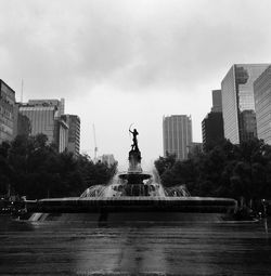 Fountain in city against sky