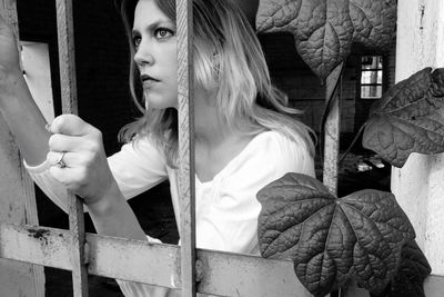 Woman looking away while standing by window 