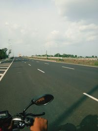 Vehicles on road against sky in city