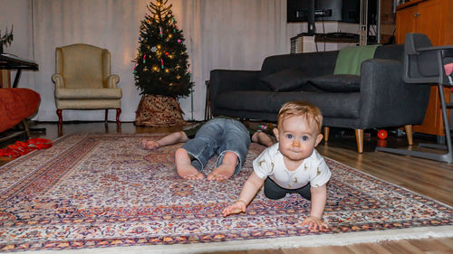 Cute boy sitting on carpet at home