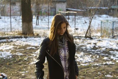 Close-up of young woman with snow on tree