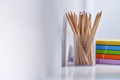 Close-up of multi colored pencils on table against wall