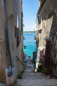 Narrow alley amidst buildings and sea against sky