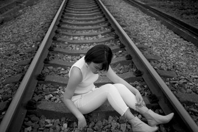 High angle view of woman sitting on railroad track