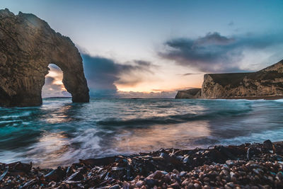 Rock formation on sea shore against sky