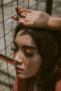 Close-up of young woman with eyes closed by fence