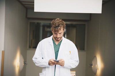 Young male doctor using mobile phone at hospital