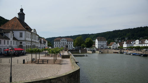 Buildings by river against sky