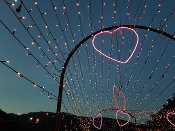 Low angle view of illuminated christmas lights against sky at night