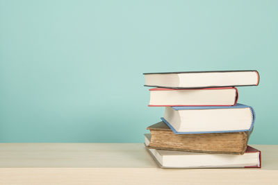 Close-up of books on table against blue wall