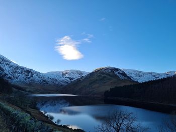 Scenic view of lake and mountains against blue sky