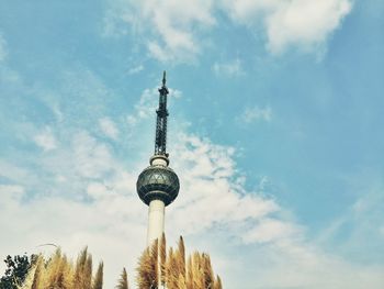 Low angle view of communications tower against cloudy sky