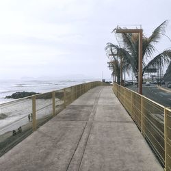 Walkway by sea against sky