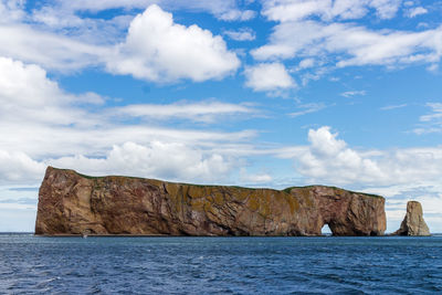 Rock formation by sea against sky