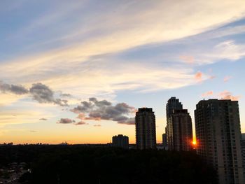 Modern buildings in city against sky during sunset