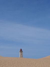 Lighthouse on beach against sky