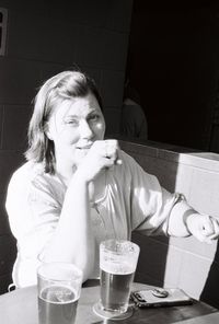 Portrait of a smiling young woman drinking glass at table