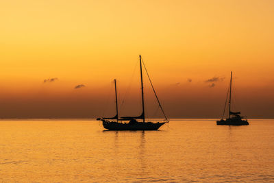 Sail boats in the calm ocean during colorful sunset