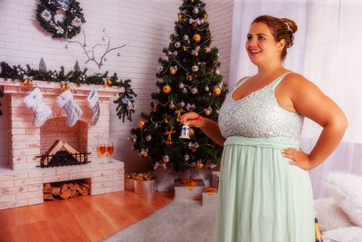 Woman standing by christmas tree at home