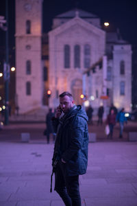 Portrait of man in warm clothing talking on mobile phone at night