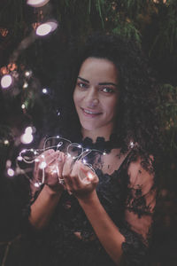Close-up portrait of beautiful woman holding illuminated lights