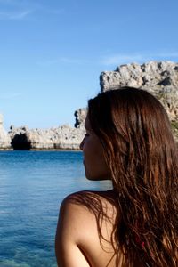 Rear view of woman standing by sea against clear sky