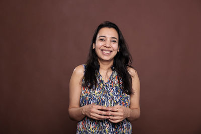 Portrait of young woman standing against black background