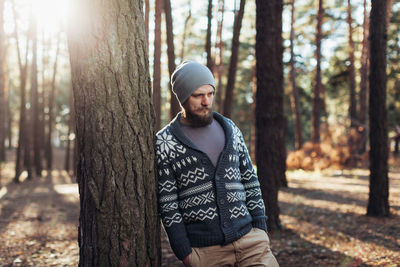 Young man standing on tree trunk in forest