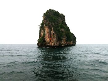 Rock formation in sea against clear sky