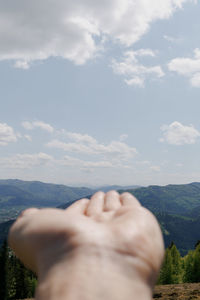 Low section of person on mountain against sky