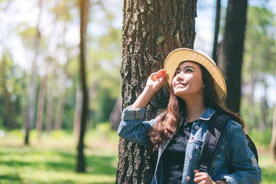 Young woman wearing hat standing in forest