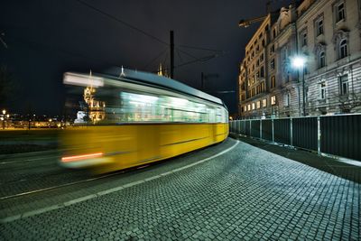 Blurred motion of train on street in city at night