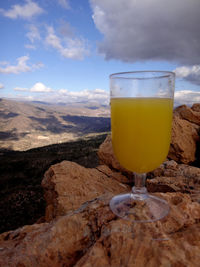 Beer glass on rock against sky