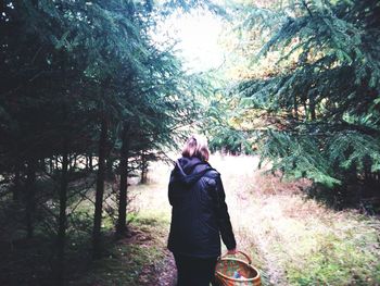 Rear view of woman standing by tree trunk