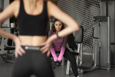 Midsection of instructor assisting woman in health club