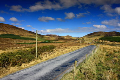 Scenic view of road by mountain against sky