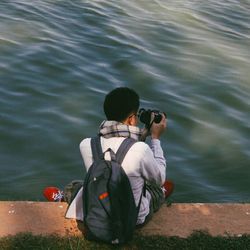 Rear view of man photographing at camera