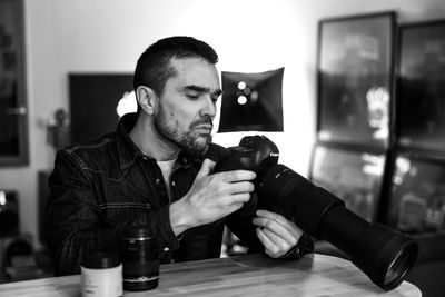 Portrait of man photographing while sitting on table at home