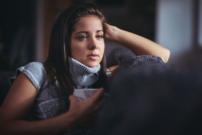 Young woman holding cup at home