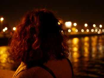 Rear view of woman standing against illuminated sky at night