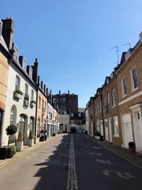 Empty road amidst buildings against sky