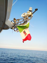 Low angle view of kite hanging over sea against clear sky
