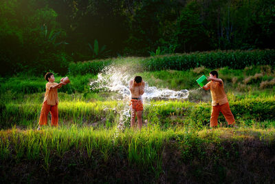 Boys throwing water on friend at farm