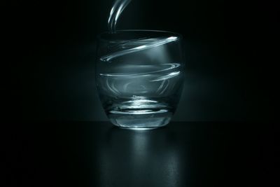 Close-up of water glass on table against black background