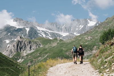 Rear view of men walking on mountain against sky