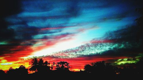 Low angle view of silhouette trees against dramatic sky