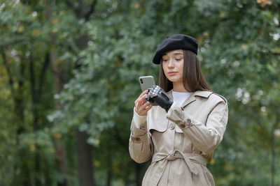 A happy european cyber woman in a raincoat with a bionic prosthesis on her arm is chatting on the